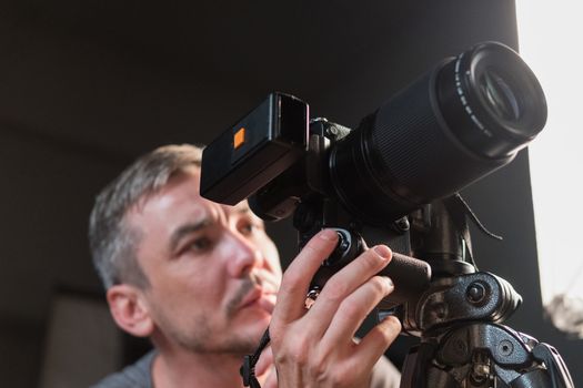 closeup of a young photographer with a camera on the background lighting equipment
