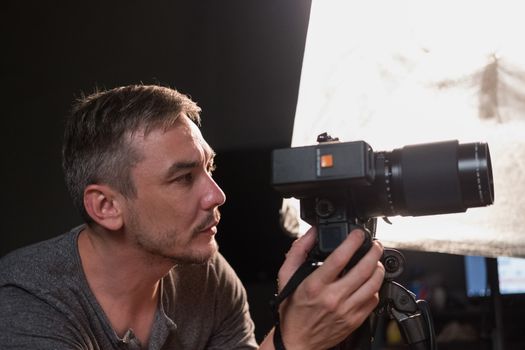 a young photographer with a camera on the background lighting equipment