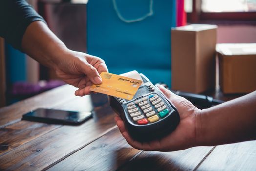 Close up of hand using credit card to pay by sending the credit card to the staff at the credit card swipe machine. Online payment