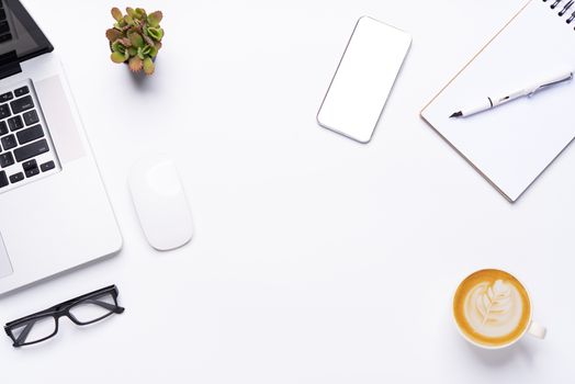 Top view with working desk with laptop,cellphone,notebook pencil coffee cup and eyeglasses in the office. 