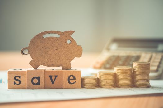 The coins are stacked and wooden blocks are pig on the wooden floor. - Savings ideas for increasing volume.