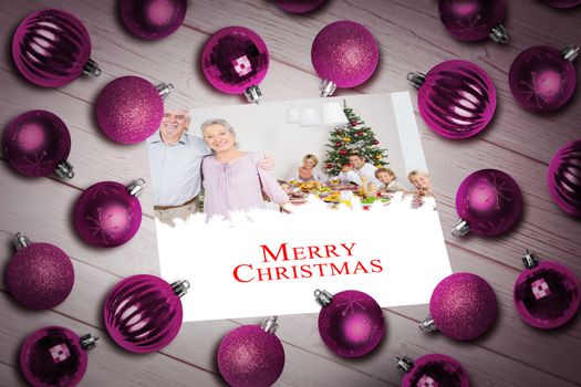 Christmas baubles on table against a happy family christmas card