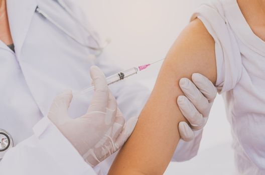 The doctor is currently treating patients by injecting arms. Vaccination or medication to prevent and treat viruses.