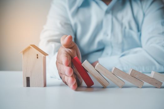  hand stopping risk the wooden blocks from falling on house, Home insurance ,security and Risk management concept.