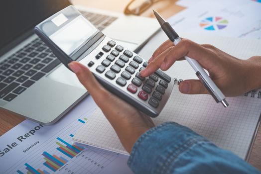 The accountant's hand is using the calculator. For cost analysis Profit and loss and tax calculation concept preparation of financial statements