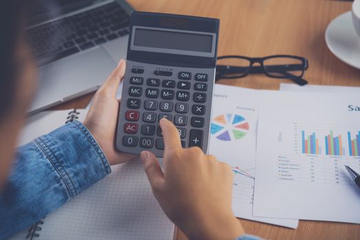 The accountant's hand is using the calculator. For cost analysis Profit and loss and tax calculation concept preparation of financial statements