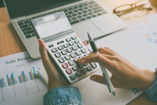 The accountant's hand is using the calculator. For cost analysis Profit and loss and tax calculation concept preparation of financial statements