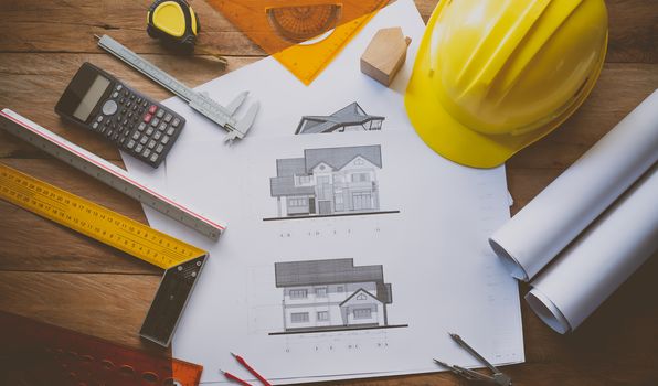 

top view House blueprint and work equipment consisting of a calculator, compass, compass, helmet, placed on a wooden floor. concept equipment of the engineers working