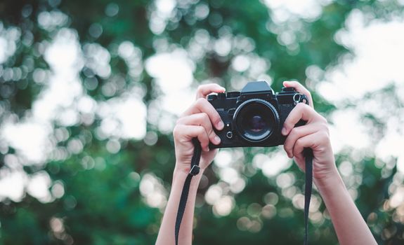 The hand that is holding up holds the old camera to take a picture.