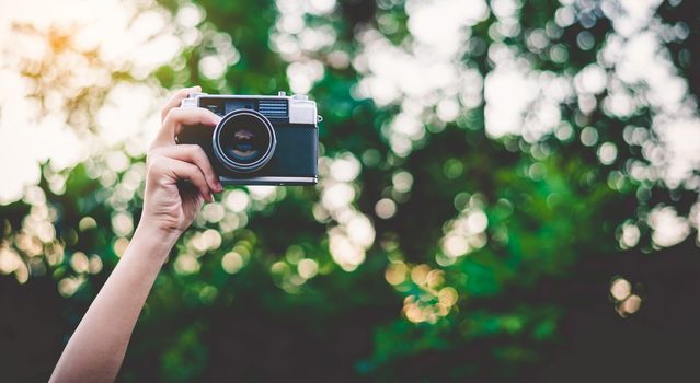 The hand that is holding up holds the old camera to take a picture.