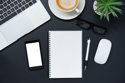 Top view with laptop, mobile phone, coffee cup, pencil, pencil and glasses placed on a black background