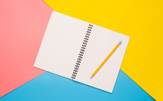 White notebooks and pencil laying on  color background