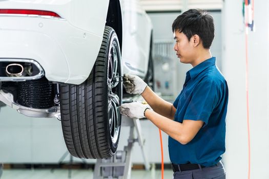 Asian mechanic checking and repairing the car wheels in maintainance service center which is a part of showroom, technician or engineer professional work for customer, car repair and maintain concept