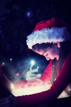 Little girl opening a magical christmas gift against christmas tree design