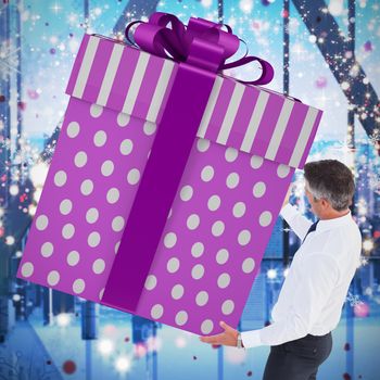 Stylish man with giant gift against glittering lights in room