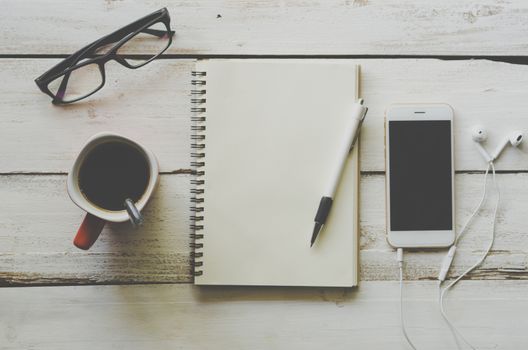 Pen on the notebook With a cup of coffee Placed on a white wooden floor.