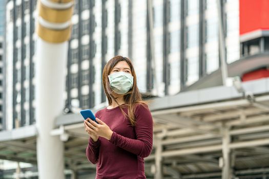 Asian woman hand using smart mobile phone with safety medical face mask for prevent Coronavirus or Covid19 Outbreak when travel to work in business downtown, Health care and infection concept