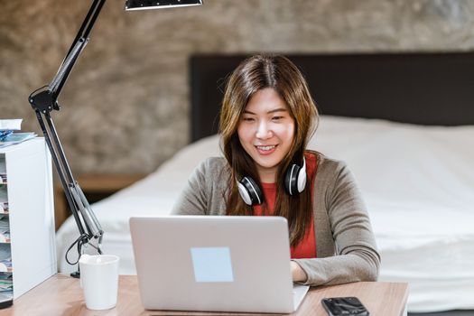 Asian business woman using technology laptop and working from home in indoor bedroom,freelance and entrepreneur,startups and business owner,lifestyle occupation,social distance and self responsibility