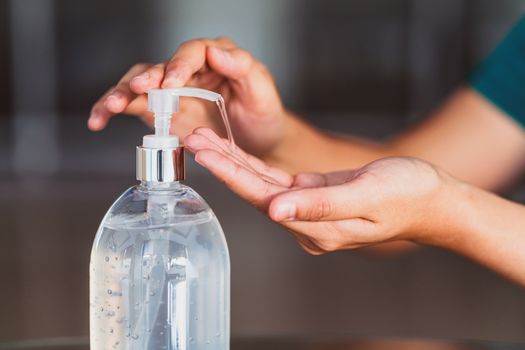 Closeup Asian woman hand using wash hand sanitizer gel pump dispenser before work over 
photo blurred of workplace while Coronavirus Network Outbreak, health care and covid19 concept