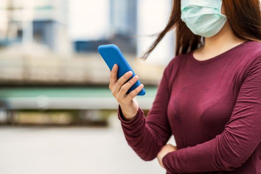 Closeup Asian woman hand using smart mobile phone with safety medical face mask for prevent Coronavirus or Covid19 Outbreak when travel to work in business downtown, Health care and infection concept