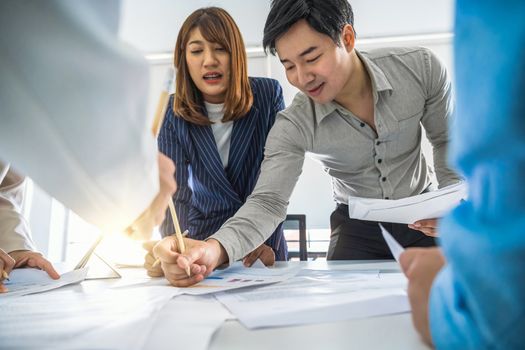 Group of Asian business people are working and brainstorming together over the document paper of project planning in office meeting room, Business meeting and workshop, project success and achievement