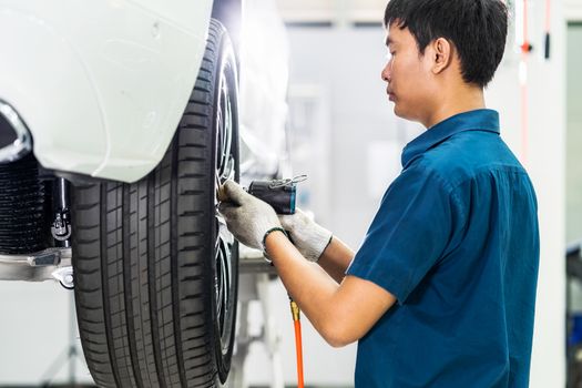 Asian mechanic checking and repairing the car wheels in maintainance service center which is a part of showroom, technician or engineer professional work for customer, car repair and maintain concept