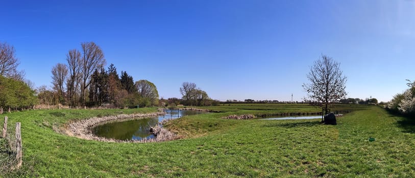 Beautiful high resolution panorama of a northern european country landscape with fields and green grass.