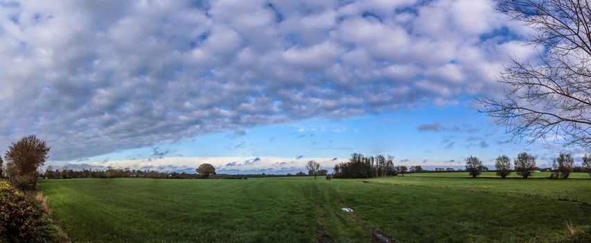 Beautiful high resolution panorama of a northern european country landscape with fields and green grass.