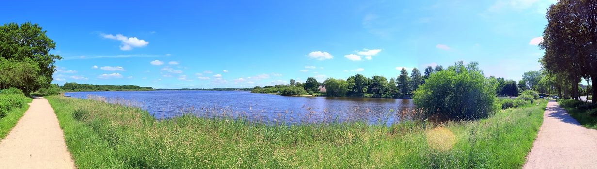 Beautiful high resolution panorama of a northern european country landscape with fields and green grass.