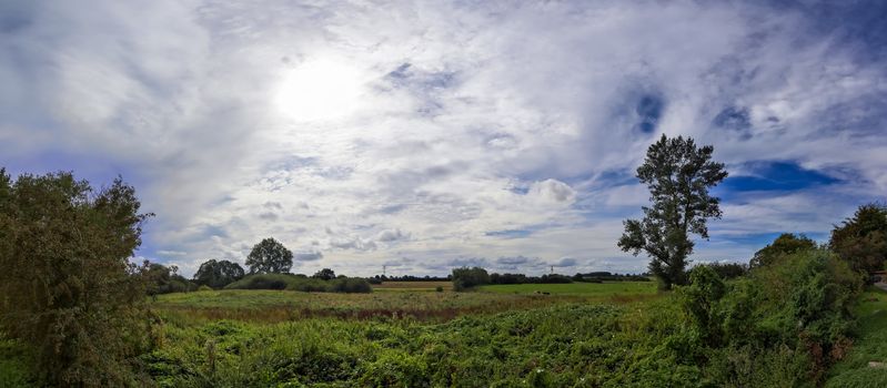 Beautiful high resolution panorama of a northern european country landscape with fields and green grass.