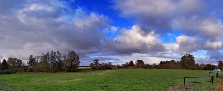 Beautiful high resolution panorama of a northern european country landscape with fields and green grass.