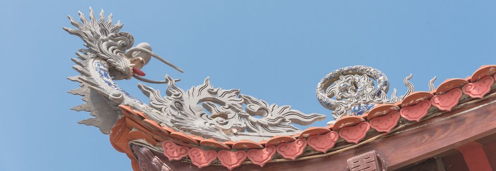 Panorama view typical cornice roof of Asian temple with dragon head shape, ancient tile roof and wooden structure. Look up view traditional pagoda exterior in the North Vietnam.