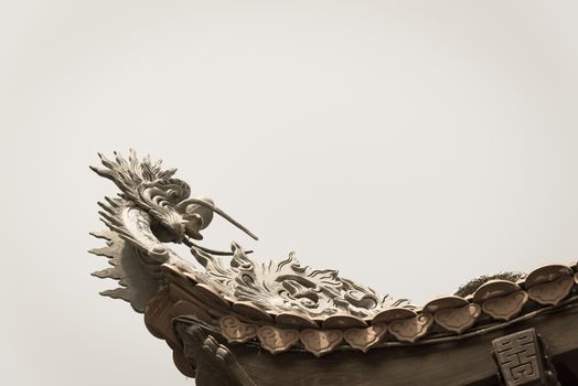 Typical cornice roof of Asian temple with dragon head shape, ancient tile roof and wooden structure. Look up view traditional pagoda exterior in the North Vietnam.