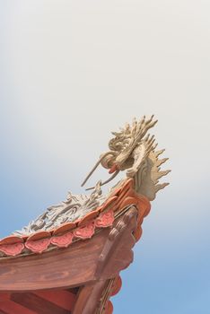 Typical cornice roof of Asian temple with dragon head shape, ancient tile roof and wooden structure. Look up view traditional pagoda exterior in the North Vietnam.
