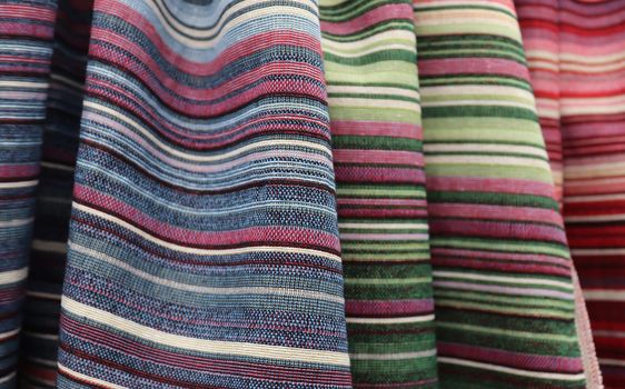 Detailed close up view on samples of cloth and fabrics in different colors found at a fabrics market.