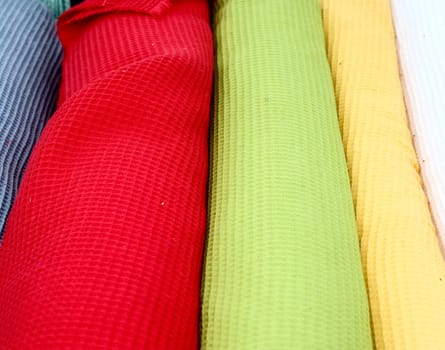 Detailed close up view on samples of cloth and fabrics in different colors found at a fabrics market.