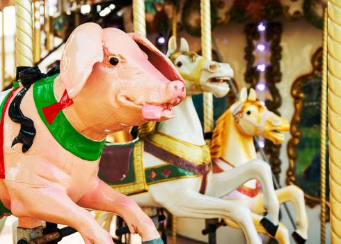 Bright pink pig and two horses at vintage carousel, retro feel and look.