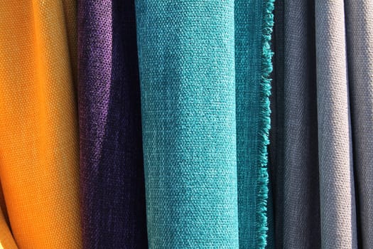 Detailed close up view on samples of cloth and fabrics in different colors found at a fabrics market.