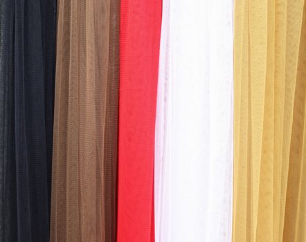 Detailed close up view on samples of cloth and fabrics in different colors found at a fabrics market.