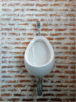 Urinal on brick wall in the restroom