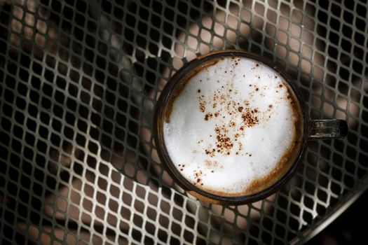 Cup of hot cappuccino coffee on steel table