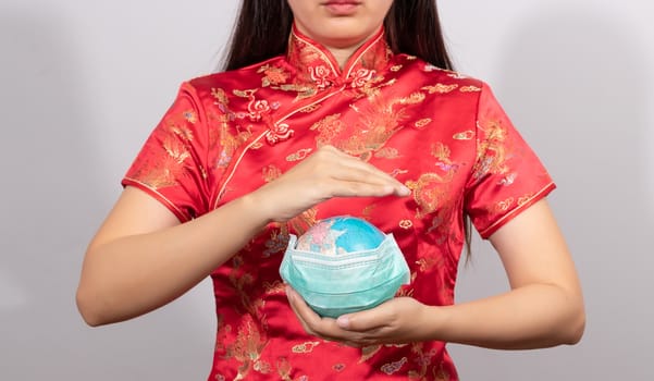 Asian woman in Chinese costume holding globe wear a hygienic mask in hand for prevent gesture. world sickness from outbreak situation of Coronavirus 2019 infection or Covid-19 concept.