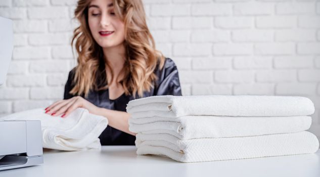 Beautiful housewife sewing towels at home using a sewing machine. Selective focus