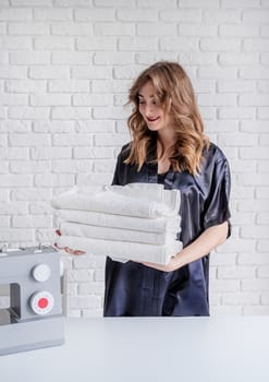 Laundry concept. Beautiful woman holding clean white towels at home