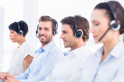Side view of a group of business colleagues with headsets in a row at office