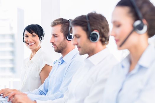 Side view of a group of business colleagues with headsets in a row at office
