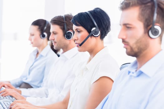 Side view of a group of business colleagues with headsets in a row at office