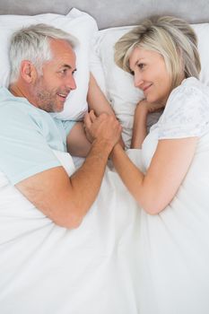 Loving mature man and woman lying in bed at the home