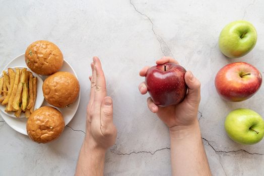 Healthy and unhealthy food concept. Apples vs french fries and burgers top view flat lay