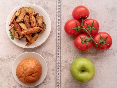 Healthy and unhealthy food concept. Fruit and vegetables vs sweets and potato fries top view flat lay with a measuring tape